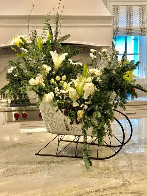 A sleigh filled with flowers is sitting on a counter in a kitchen.