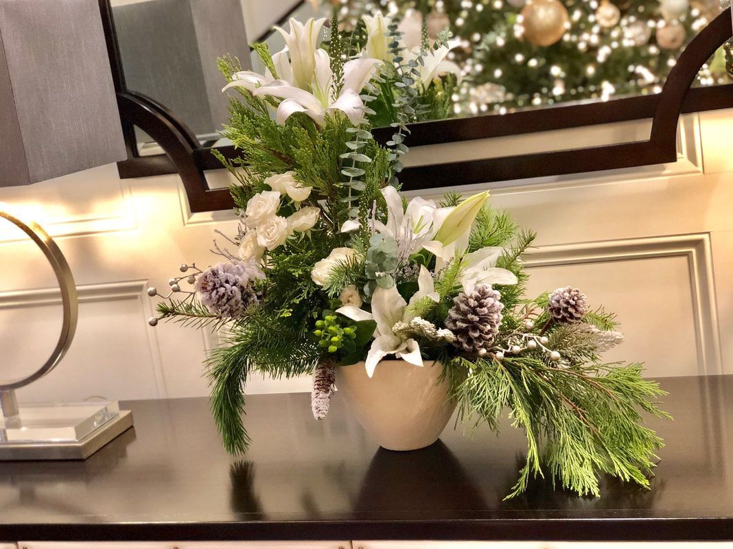 A vase filled with flowers and pine cones is sitting on a table.
