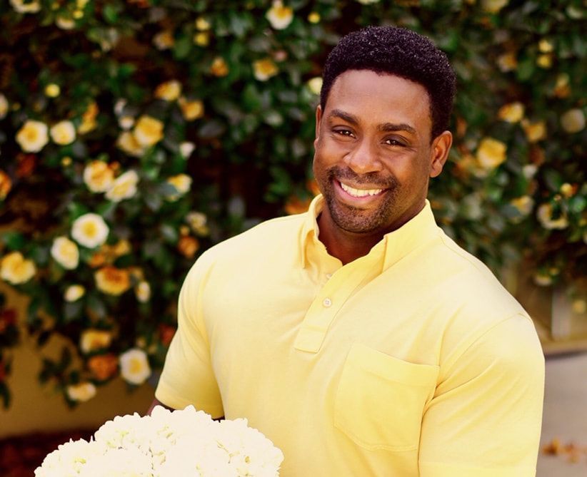 A man in a yellow shirt is holding a bouquet of white flowers.