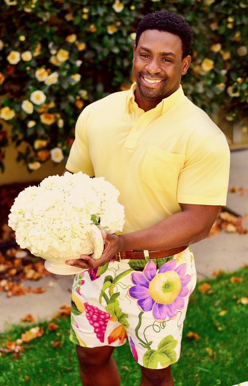 A man in a yellow shirt is holding a vase of flowers