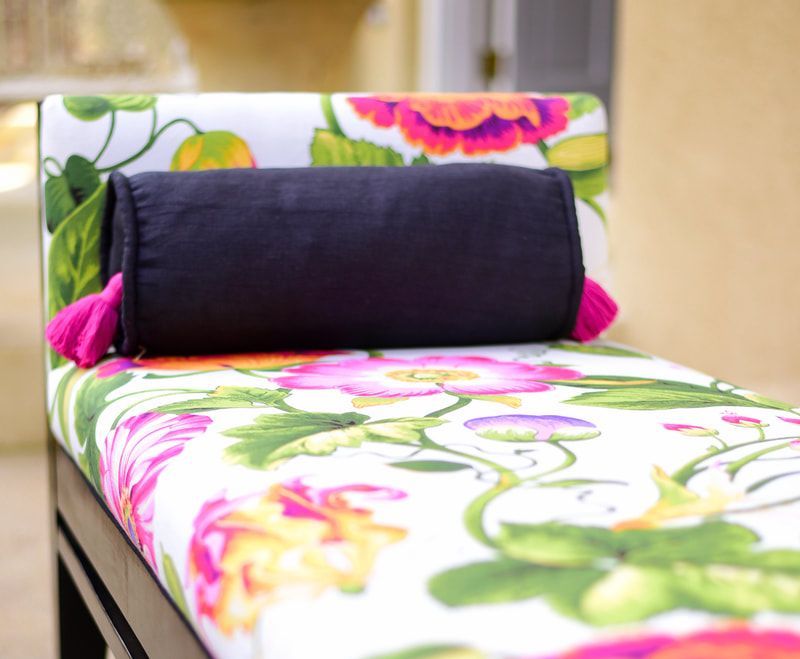 A floral bench with a black pillow on it