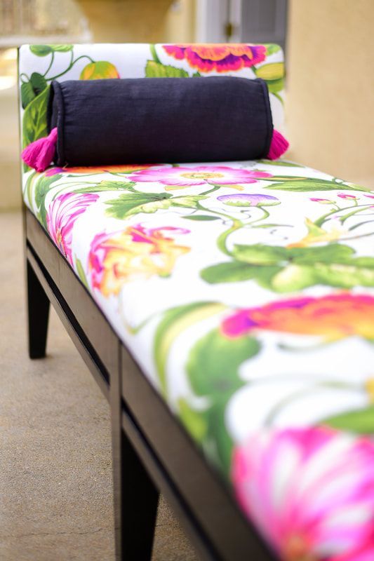A floral bench with a black pillow on it