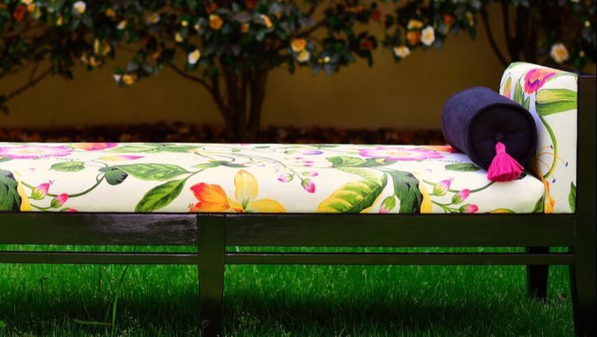A bench with a floral pattern on it is sitting in the grass.