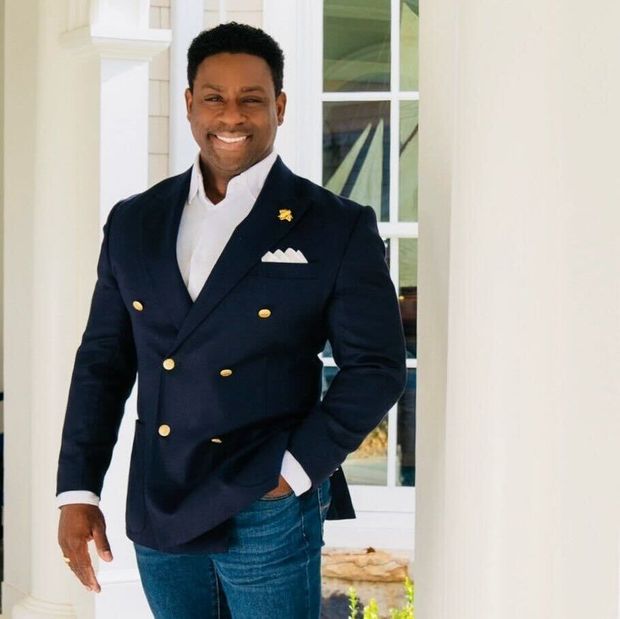 A man in a suit is standing in front of a window