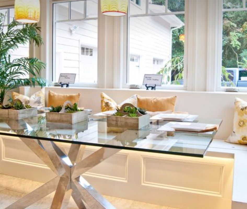 A dining room with a glass table and a bench