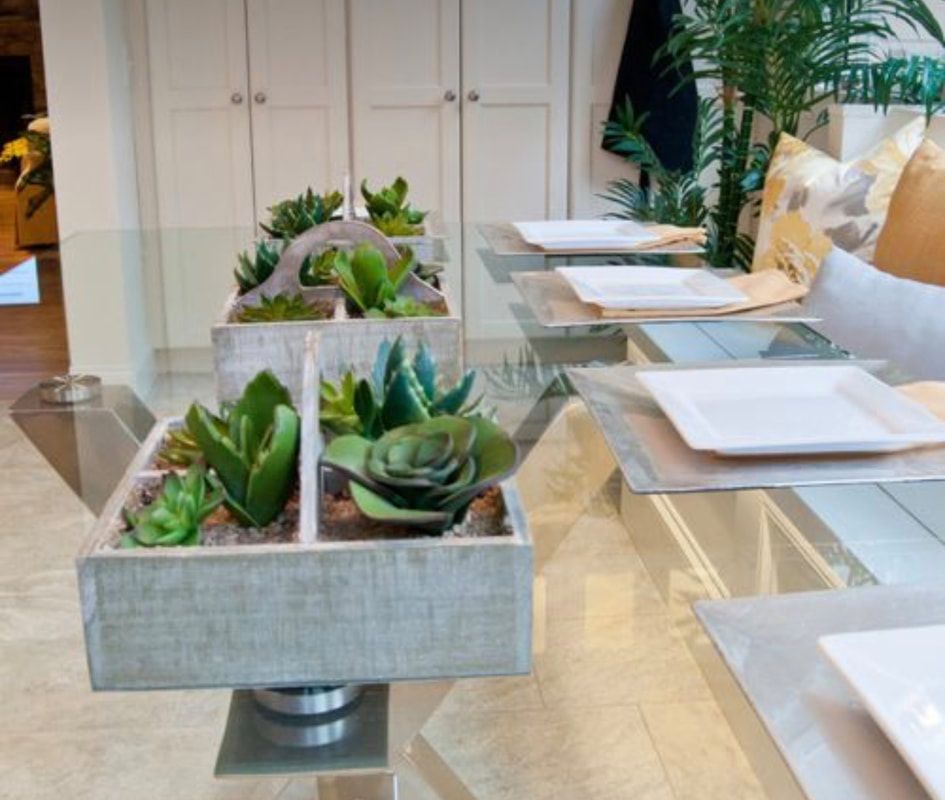 A dining room table with plates and potted plants on it