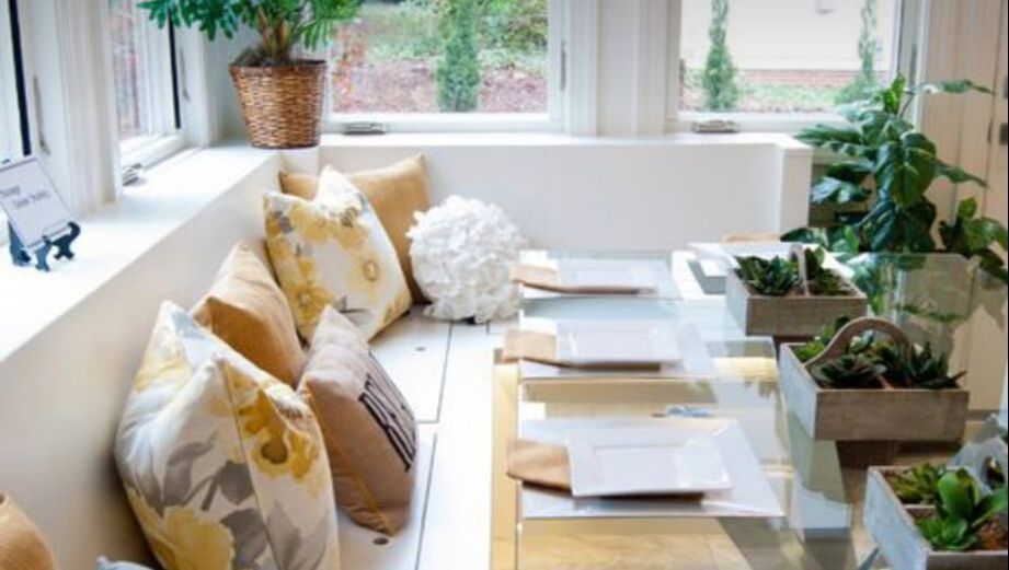 A living room with a couch , table , and potted plants.