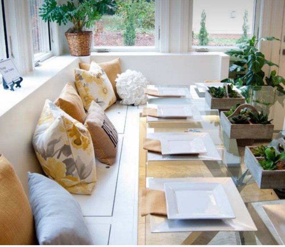 A dining room table with plates and pillows on it