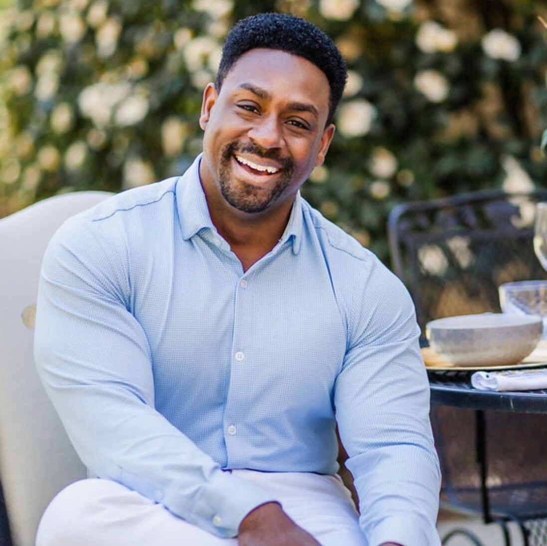 A man in a blue shirt is smiling while sitting at a table