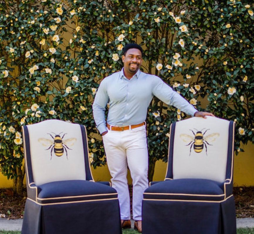A man standing next to two chairs with bees on them