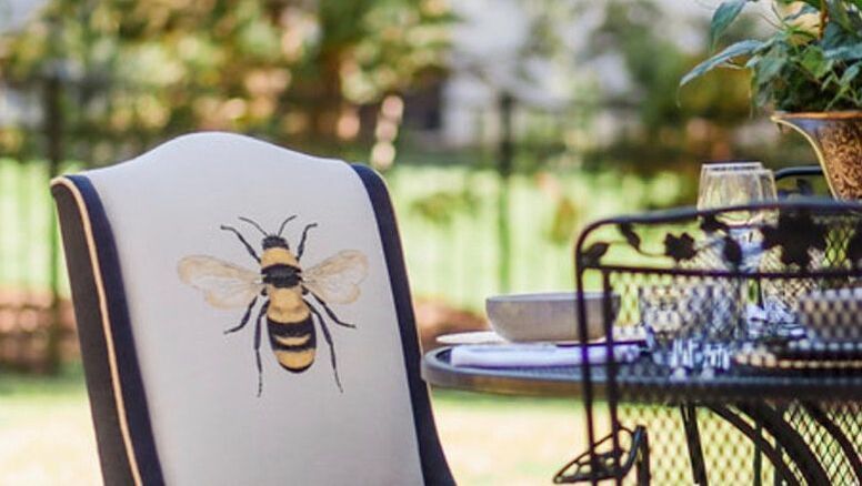 A chair with a bee on it is sitting next to a table.