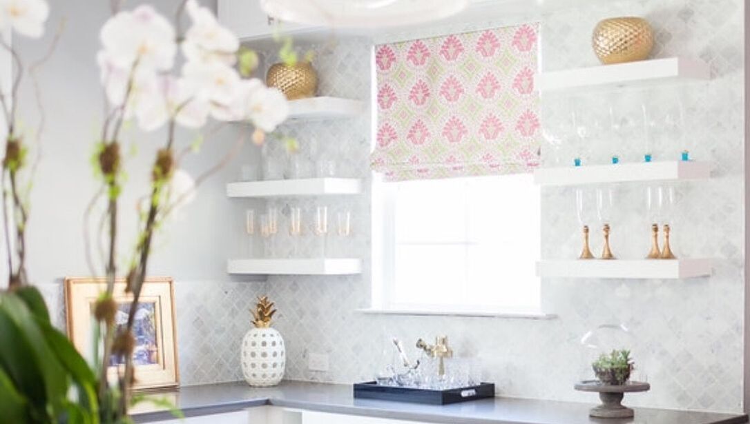 A kitchen with a window , shelves , and a vase of flowers.