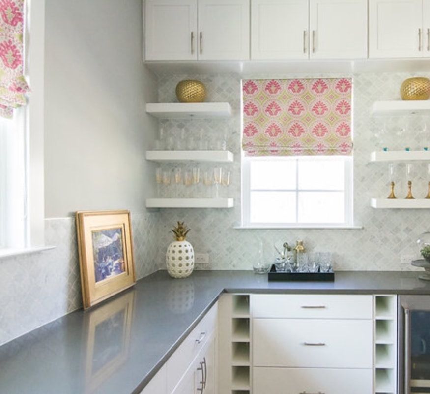 A kitchen with white cabinets and gray counter tops