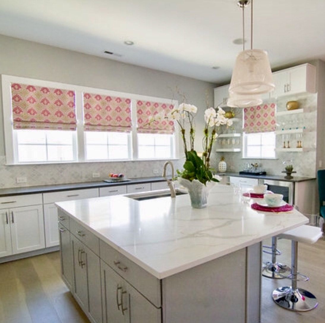 A kitchen with white cabinets and marble counter tops