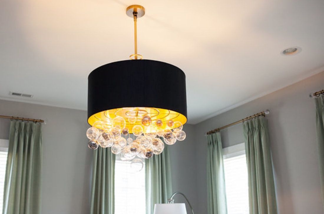 A black and gold chandelier is hanging from the ceiling in a room.
