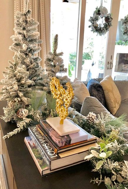 A living room decorated for christmas with a stack of books and a christmas tree.