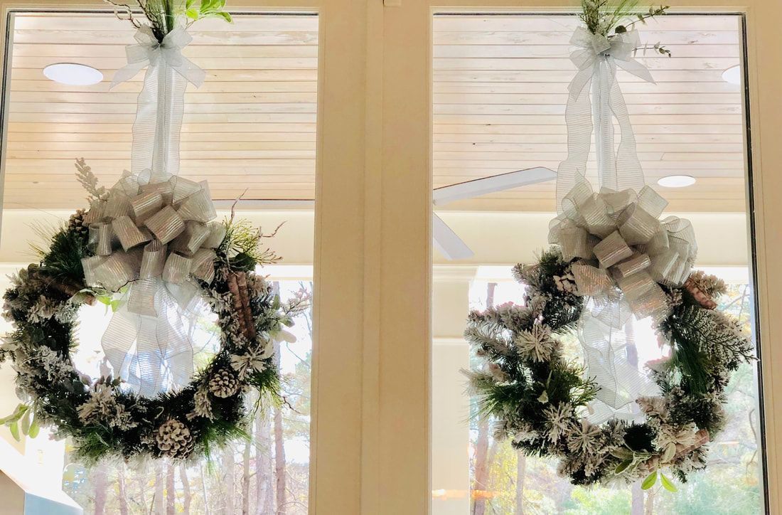Two wreaths are hanging on a door in a room.
