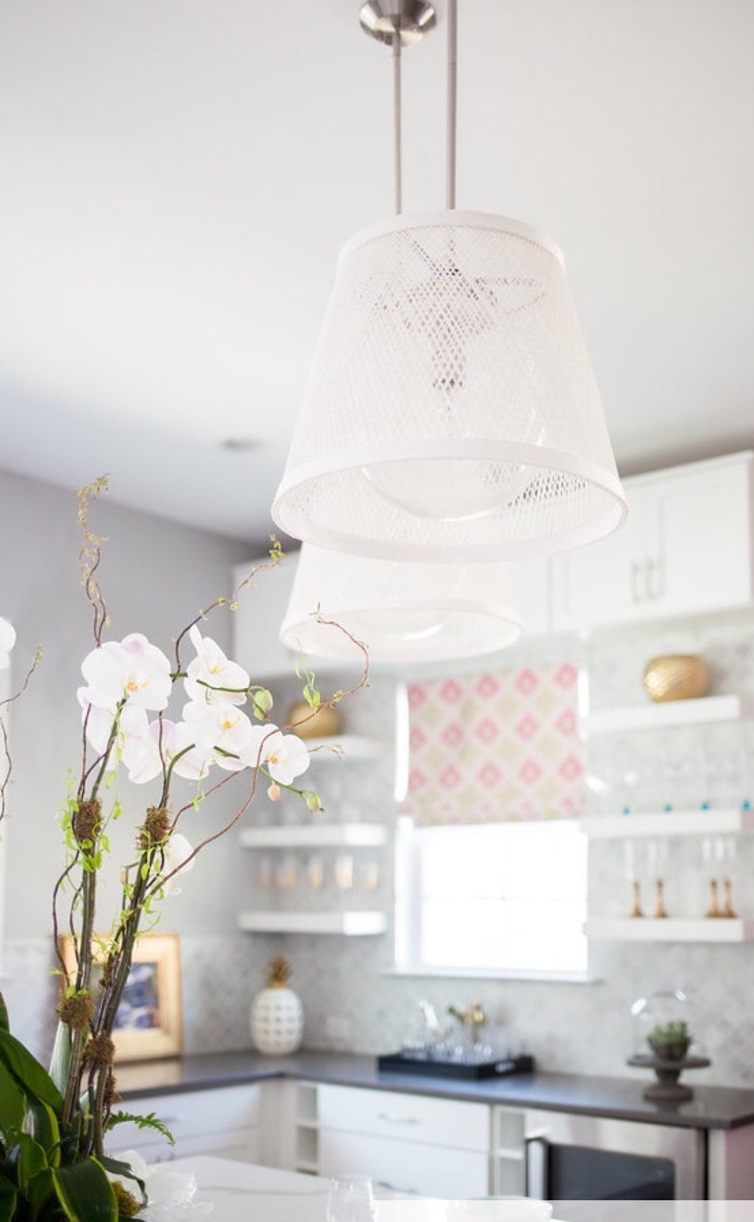 A kitchen with white cabinets and a light hanging from the ceiling