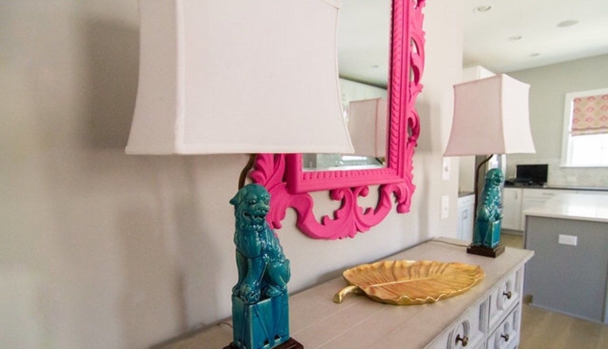 A table with two lamps and a mirror on it.
