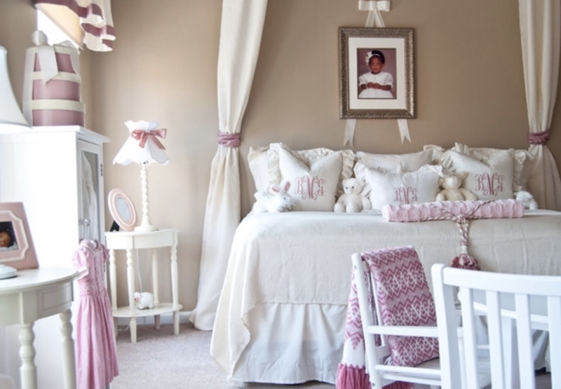 A girl 's bedroom with a canopy bed and a picture on the wall