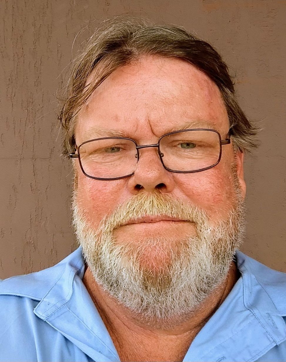 A man with glasses and a beard is wearing a blue shirt