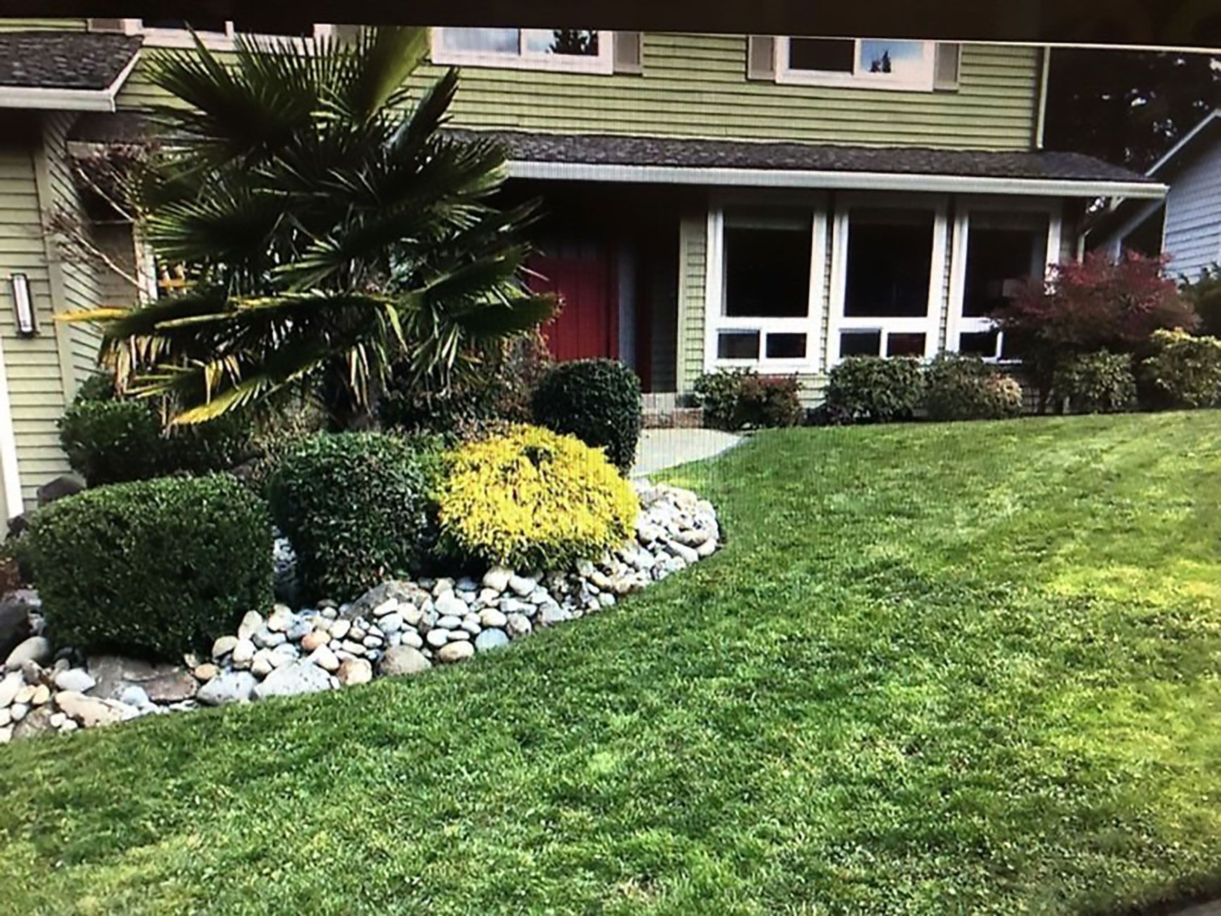 A house with a lush green lawn and rocks in front of it.