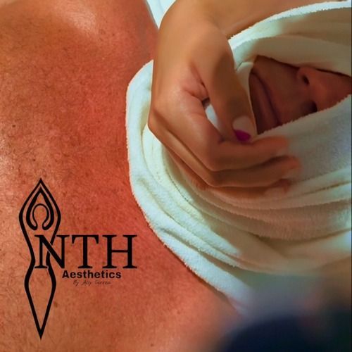 Baby swaddled in white towel, hand resting gently on the swaddle. The logo 