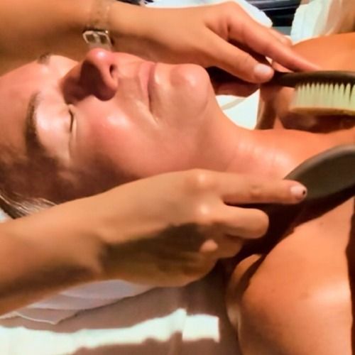 Person receiving dry brushing treatment to the neck and shoulders.