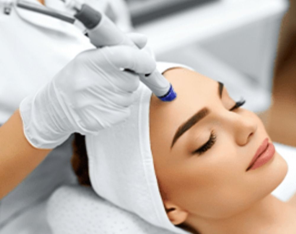 Woman receiving a facial treatment with a handheld device in a spa setting.
