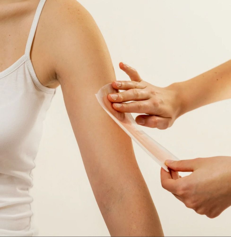 Person applying wax strip to arm.