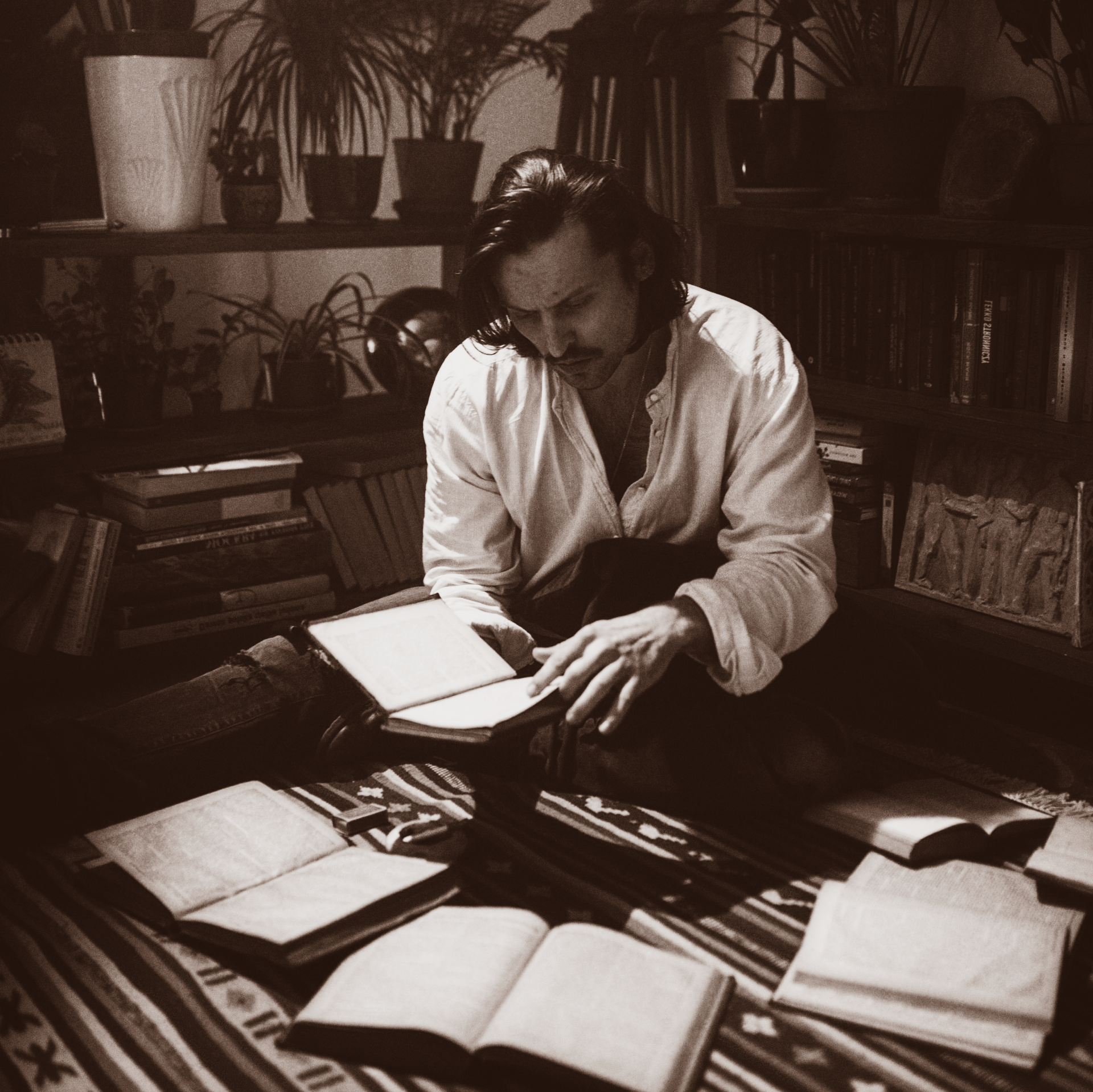 poet or story teller reading from his book surrounded by books