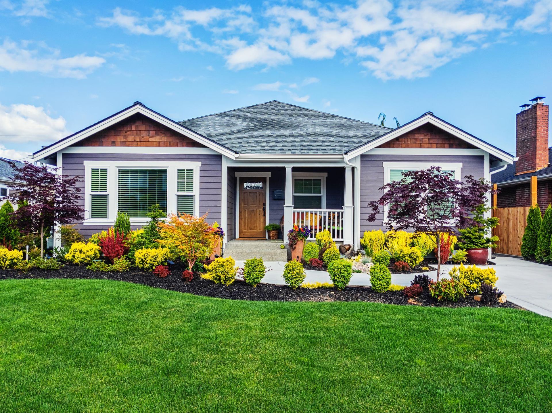 A purple house with a lush green lawn in front of it.