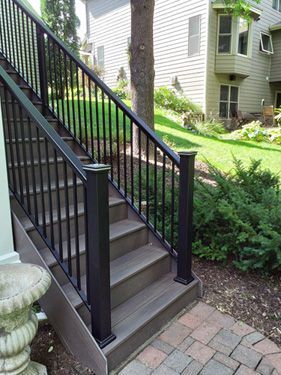 A set of stairs leading up to a house with a black railing.