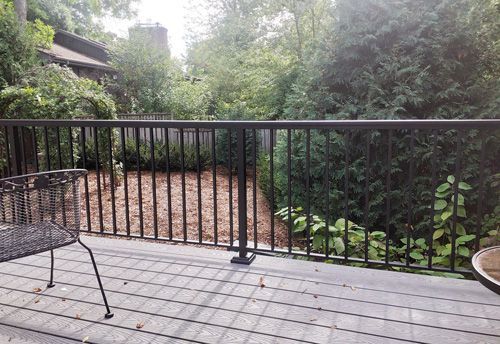 A wooden deck with a metal railing and a bench.