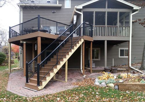 A house with a screened in porch and a deck with stairs leading up to it.
