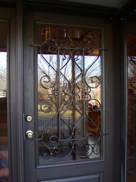 A close up of a wrought iron door with a glass window.