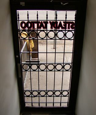 A door with a wrought iron gate that says ' ootta ' on it