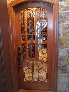 A wooden door with a wrought iron gate leading to a wine cellar.