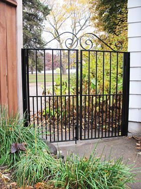 A black wrought iron gate is sitting next to a house.