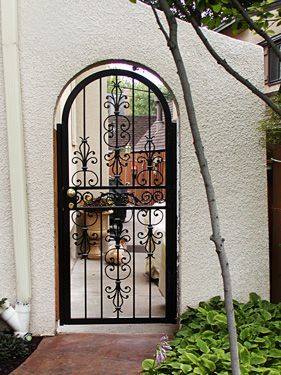 A wrought iron gate is on the side of a building