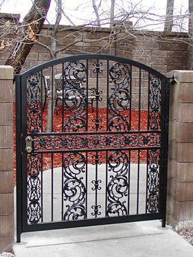 A wrought iron gate with a brick wall in the background