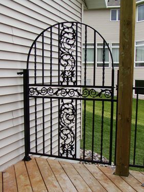 A wrought iron gate on a deck next to a house