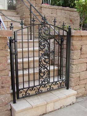 A wrought iron gate is next to a set of stairs.