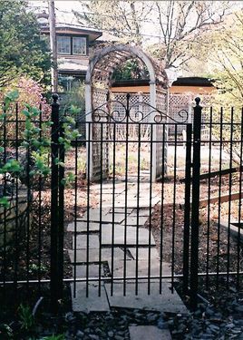 A wrought iron gate with a stone walkway behind it