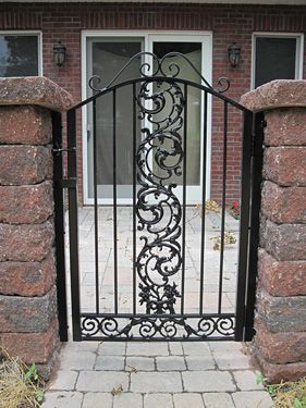 A wrought iron gate is in front of a brick building.