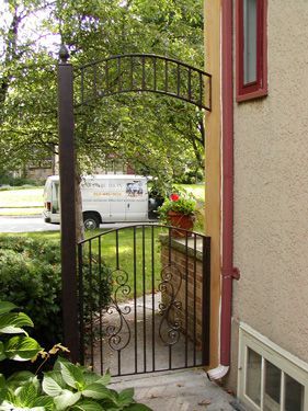 A white van is parked behind a wrought iron gate