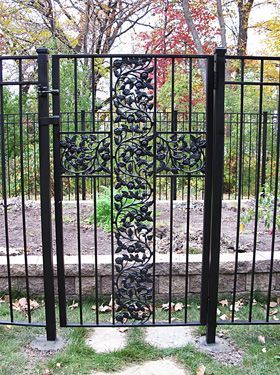 A wrought iron gate with a cross on it is surrounded by a fence.