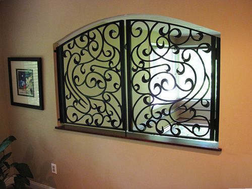 A wrought iron window with a picture on the wall behind it.