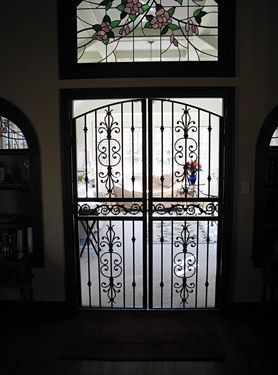 A wrought iron door with a stained glass window above it.
