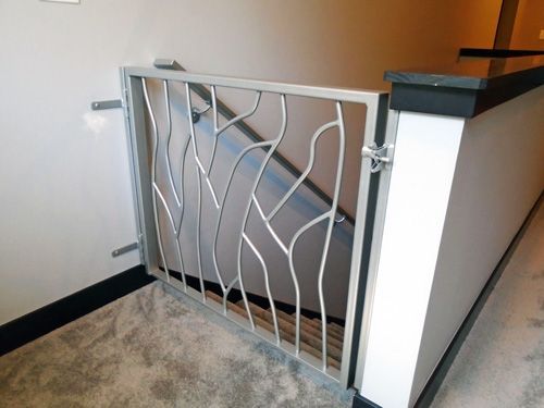 A metal gate is between two stairs in a hallway.